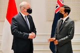 Scott Morrison and Joko Widodo stand together wearing suits and speaking to each other.