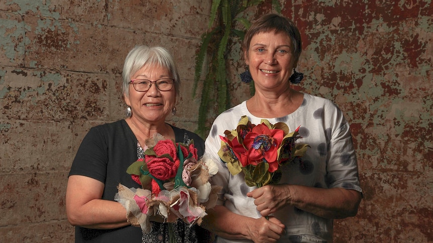 Two women holding bouquets of handmade flowers.