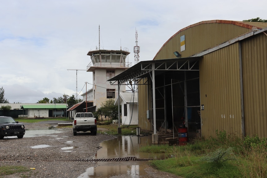 A control tower and large corrugated iron hangar at the Dili heliport.