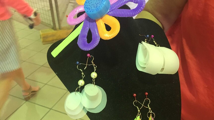 A black display holder showing earrings made out of various plastic items