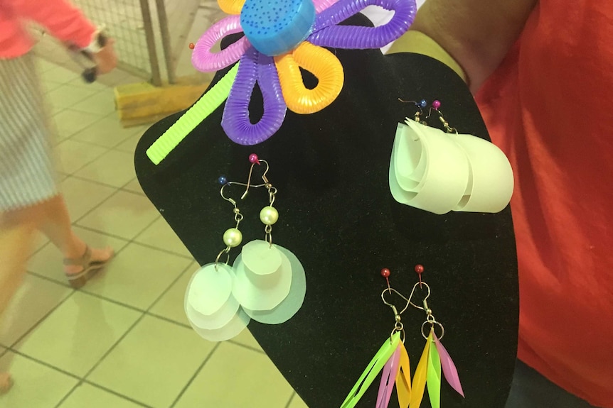 A black display holder showing earrings made out of various plastic items