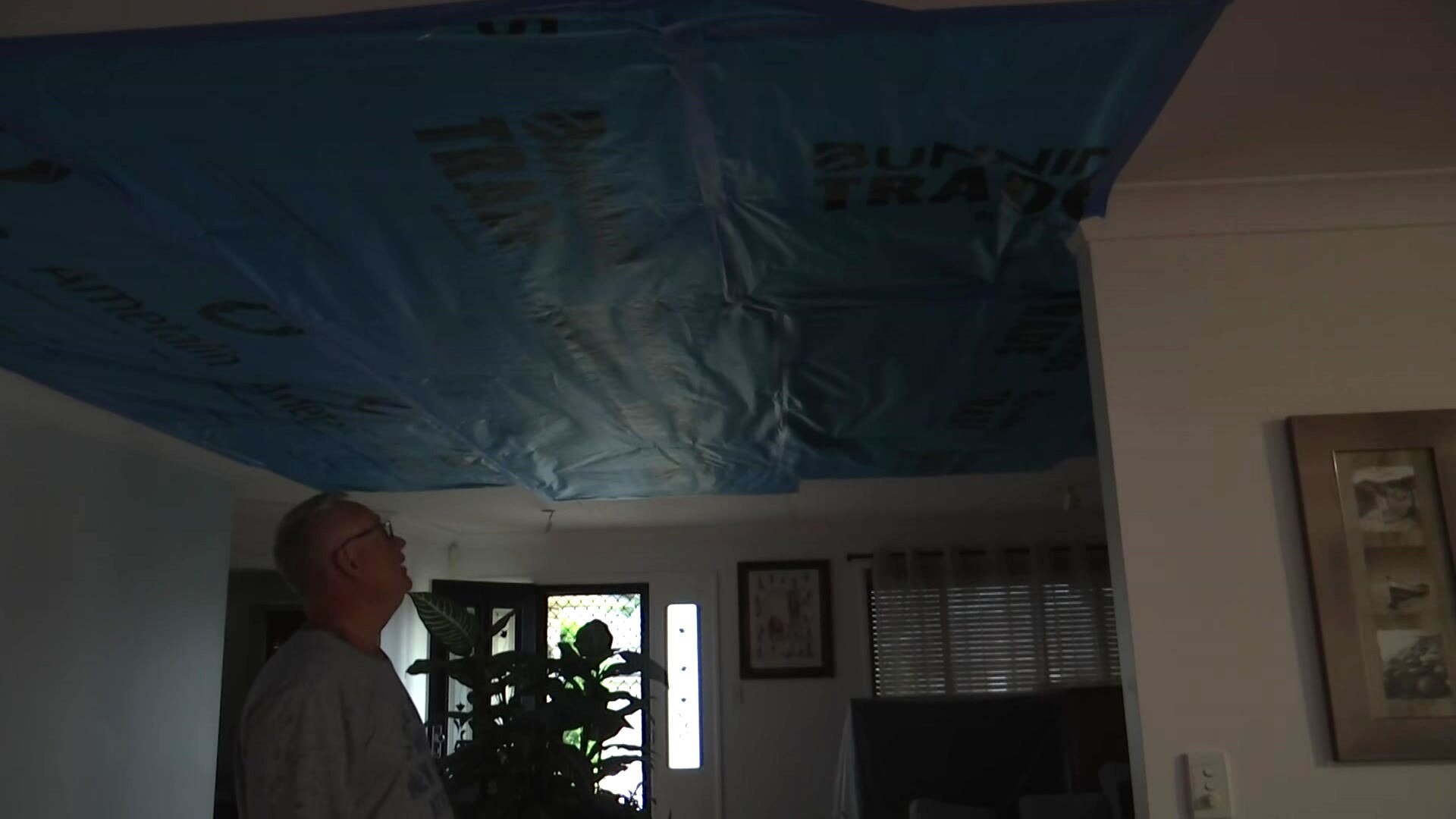 Denis Fogarty looks up at the tarp on his roof