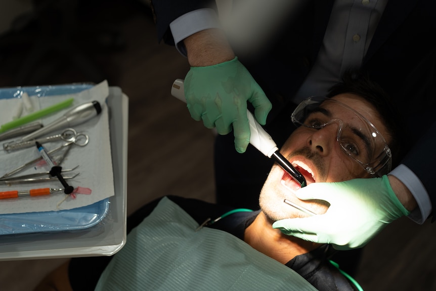 Man in dentist chair with a dentist above him.