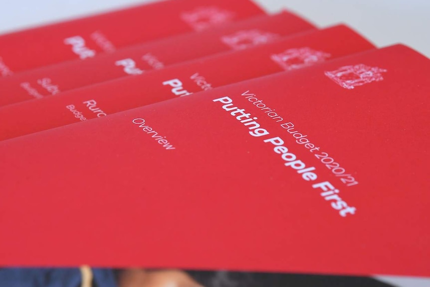 Red covered Budget books labelled 'Putting People First' are laid on a table in a fanned-out pile.