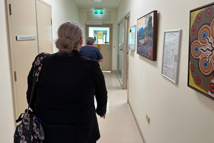 A woman walks down a hospital hallway