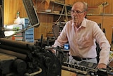 Hillston Spectator editor Patrick O'Sullivan standing next an old printing device