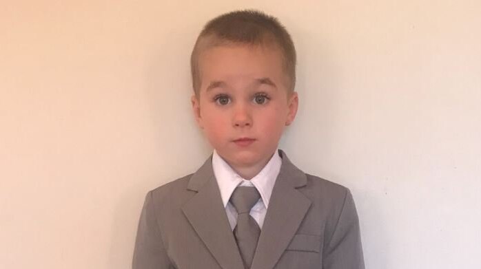 A three year old boy with sandy hair wearing a business suit