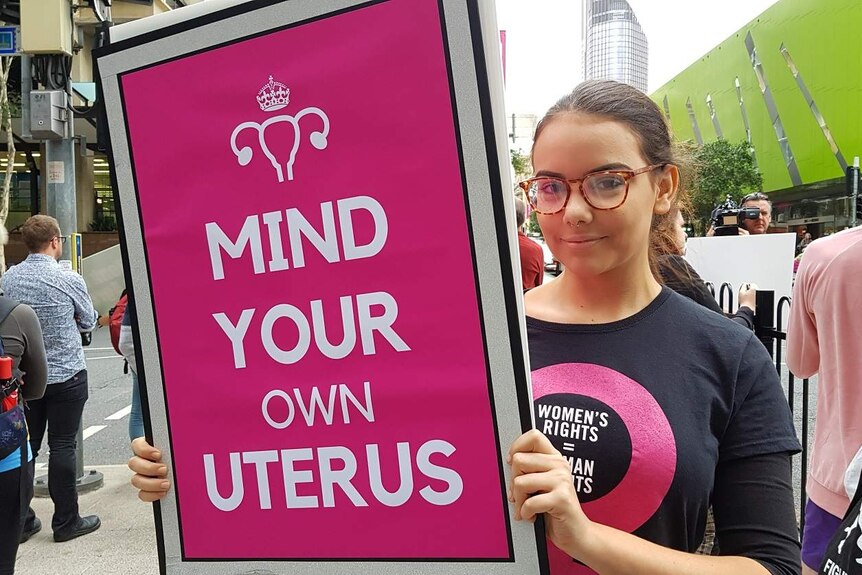 Tiyana Jovanovic campaigns with a sign saying Mind Your Own Uterus at a pro choice rally in Brisbane on June 26, 2018.
