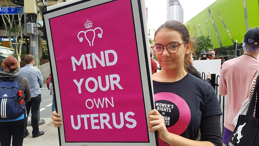 Tiyana Jovanovic campaigns with a sign saying Mind Your Own Uterus at a pro choice rally in Brisbane on June 26, 2018.