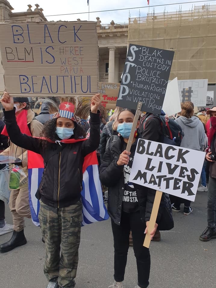 Two girls holding up Black Lives Matter, and Black Is Beautiful signs, with #Free Papua, at a protest