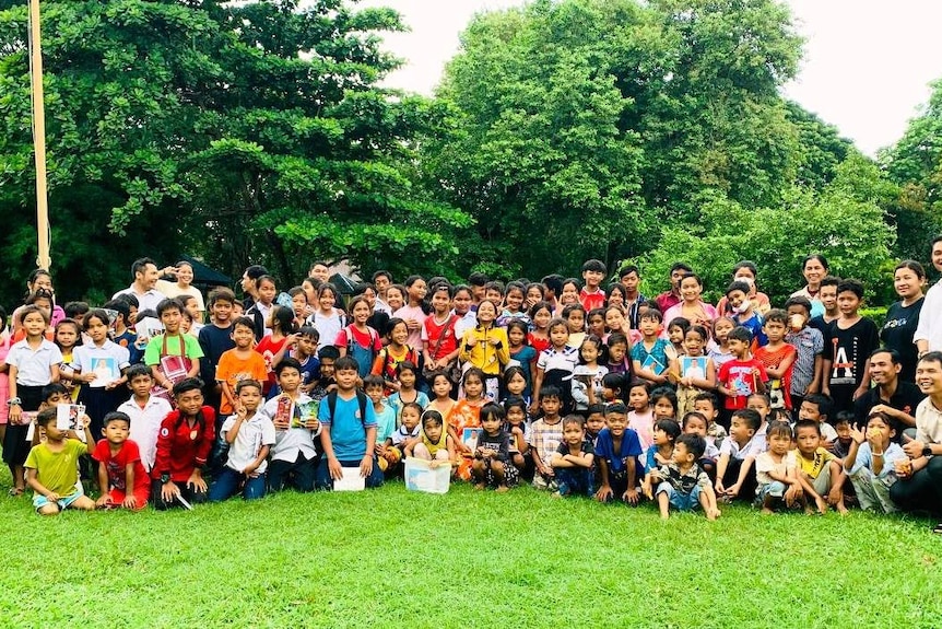 a group photo of children and volunteers in a park