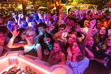 a group of young women and men stand in front a dj dancing