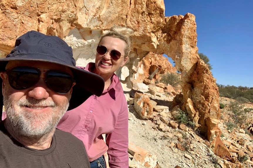 Two people in front of weathered rocks.