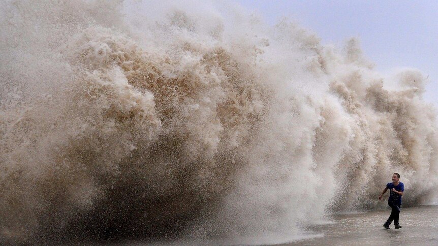 A man runs away from a huge wave pushed up by Typhoon Usagi.
