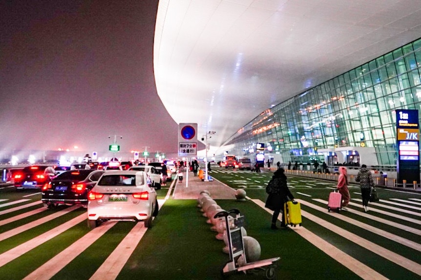 The exterior of an airport with passengers walking into the terminal