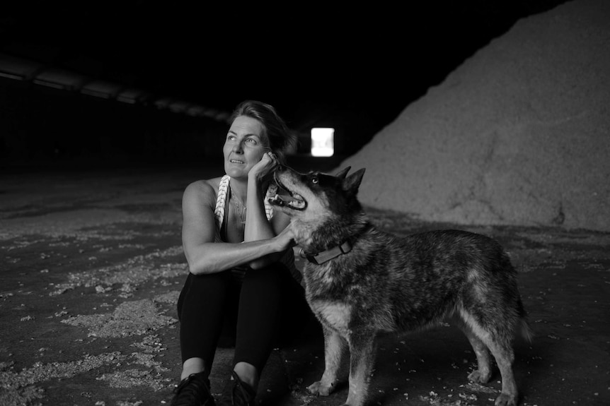 A black and white image of a woman sitting with a dog