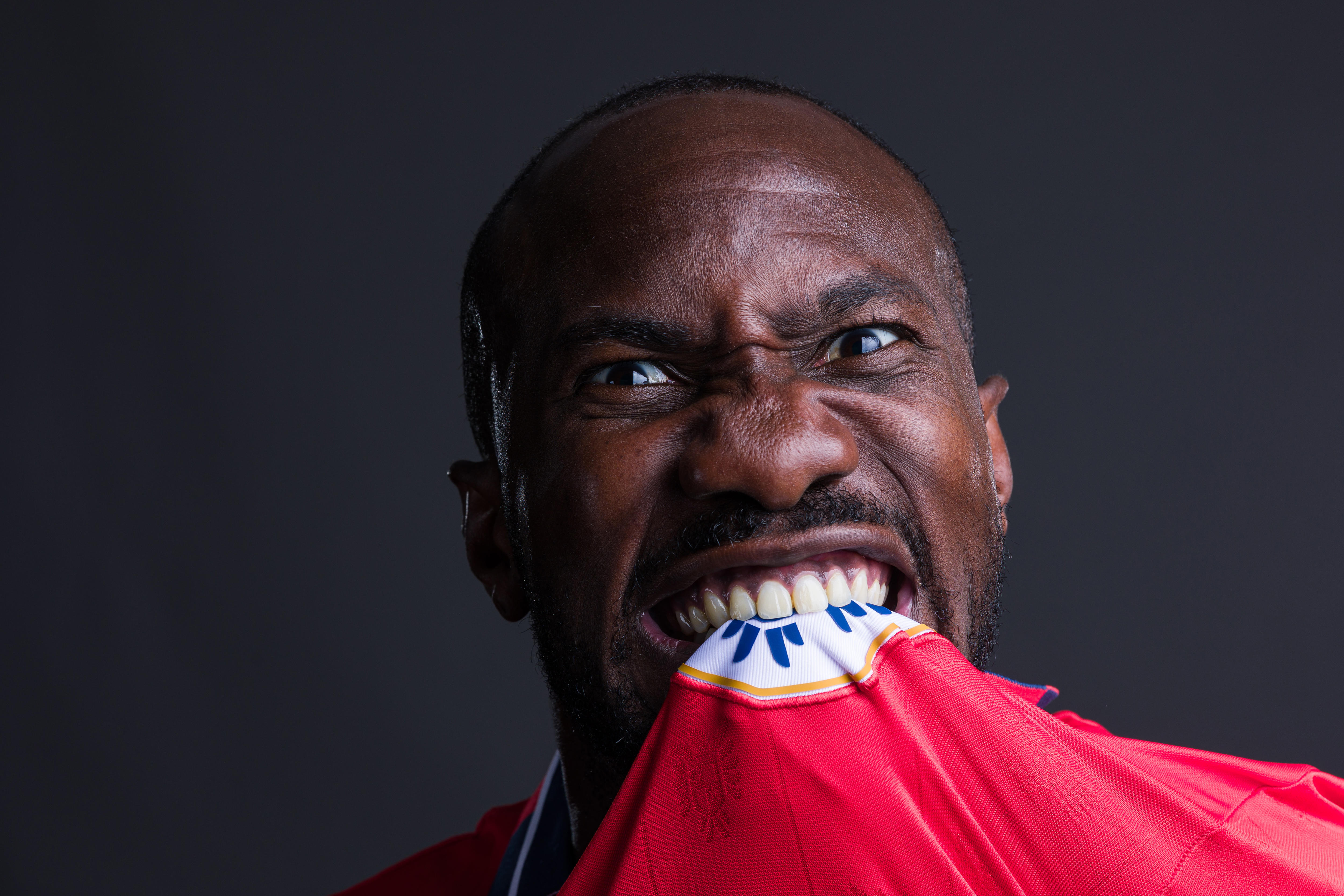 Cecilio Waterman bites the crest on his jersey in a photoshoot
