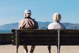 Two older people sitting on a bench, looking in different directions for story on effect of divorce on adult children