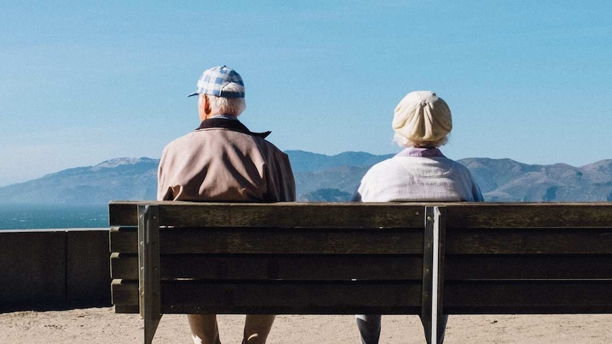 Two older people sitting on a bench, looking in different directions for story on effect of divorce on adult children