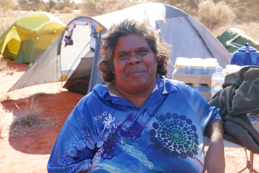 A woman sitting on a chair at a camp.