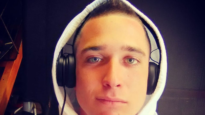 Jordan Battisson with headphones and a white, sleeveless hoodie.