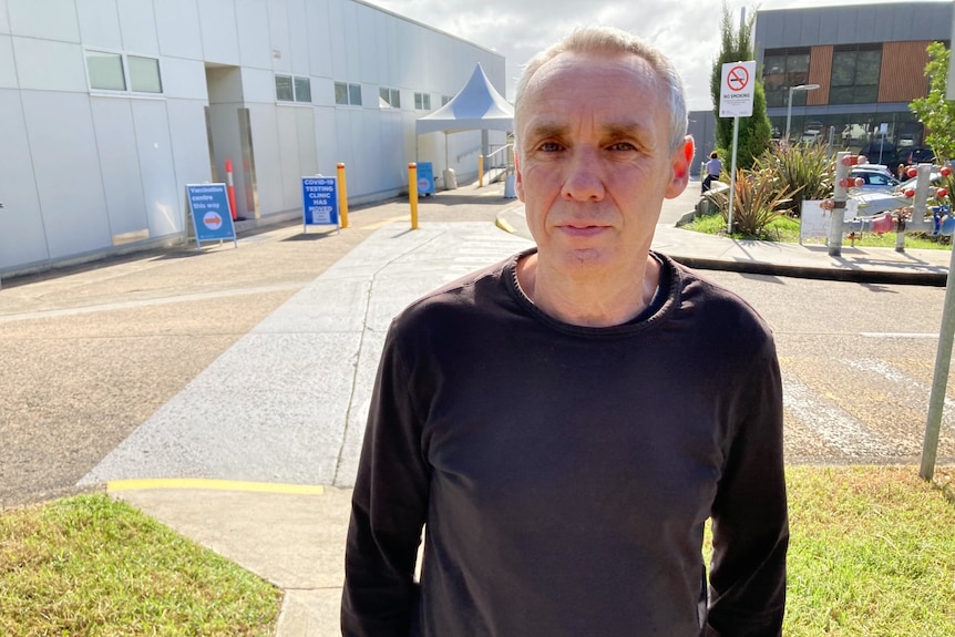 a man standing outside a covid clinic looking stern