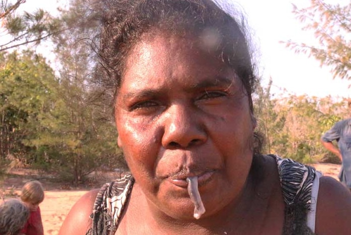 Aboriginal woman eating slimy, grey worm.