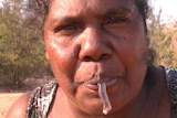 Aboriginal woman eating slimy, grey worm.
