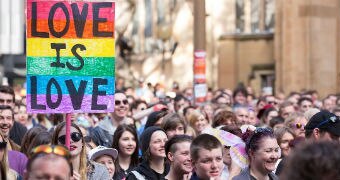 Same-sex marriage activists march in the street during a rally in Sydney, with one holding a rainbow sign saying "Love is love".
