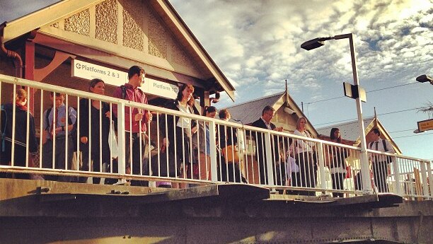 Passengers wait on the overhead bridge as announcements are made about train delays at Gordon station in Sydney.
