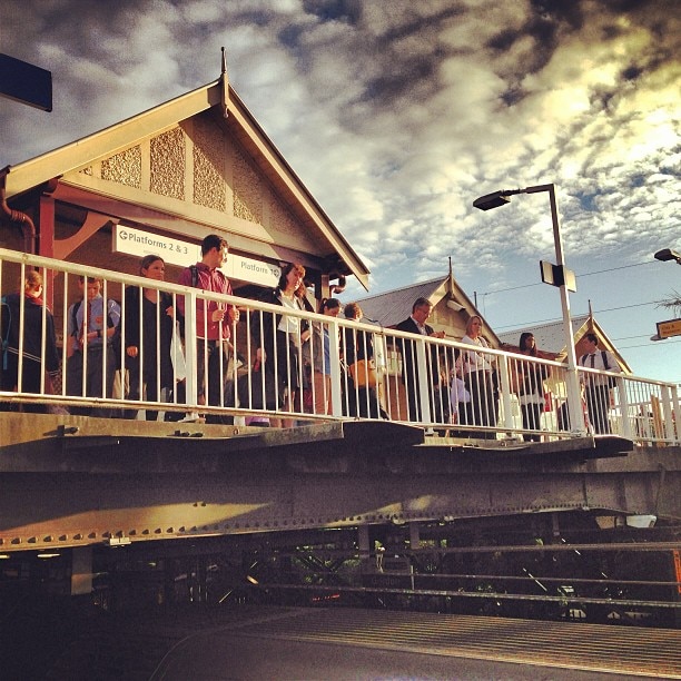 Passengers wait on the overhead bridge as announcements are made about train delays at Gordon station in Sydney.