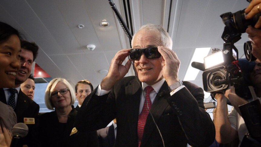 Malcolm Turnbull at an engineering technology facility trying on sunglasses