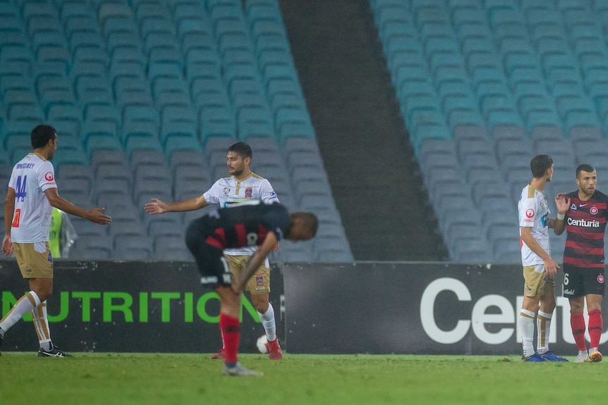 End of the match players embrace empty stadium.