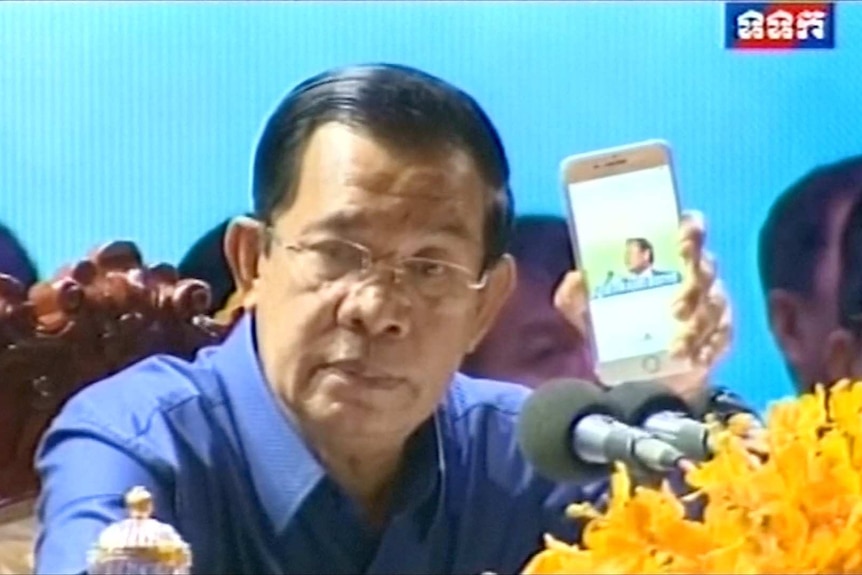 Prime Minister Hun Sen plays video of Kem Sokha's speech in Melbourne on a smart phone.