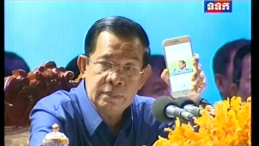 Prime Minister Hun Sen plays video of Kem Sokha's speech in Melbourne on a smart phone.