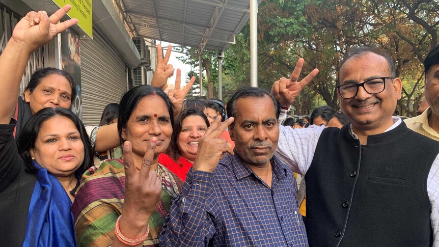 People in a street in India showing the peace sign with their fingers.