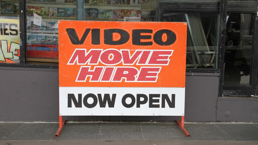 A large sign stands on the footpath outside a window