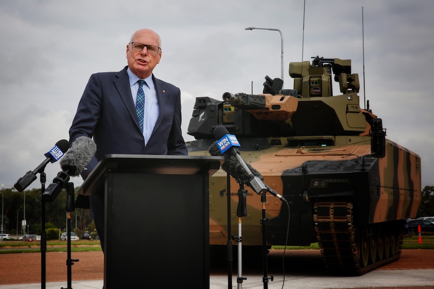 Jim Molan speaks at a press confernece in front of military vehicles