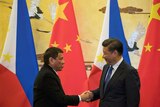 Rodrigo Duterte (L) and Chinese President Xi Jinping shake hands after a signing ceremony.