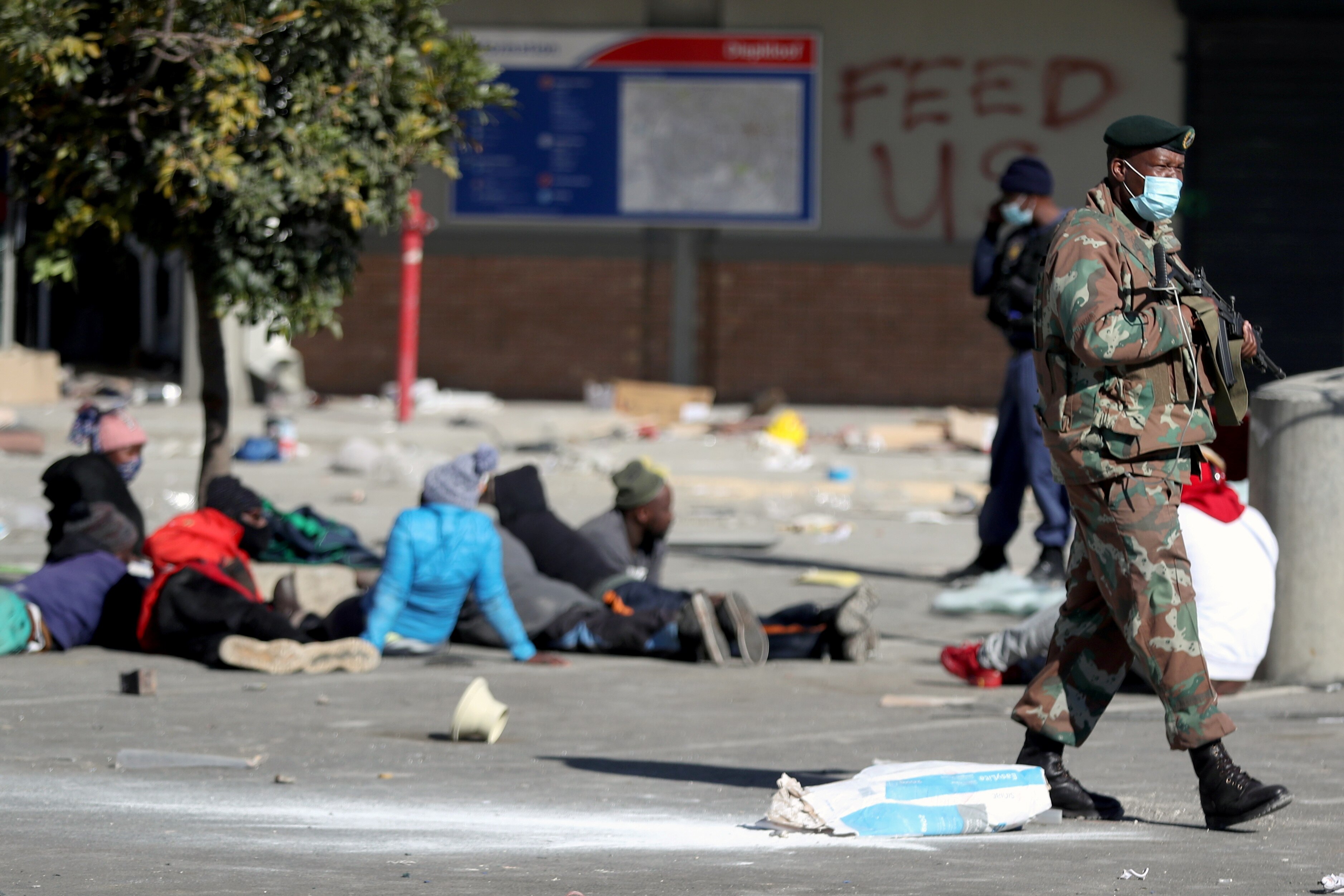 Protesters sit on the ground as a soldier walks behind them