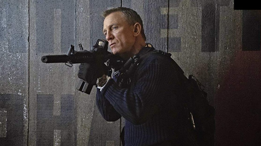 Daniel Craig holds a machine gun