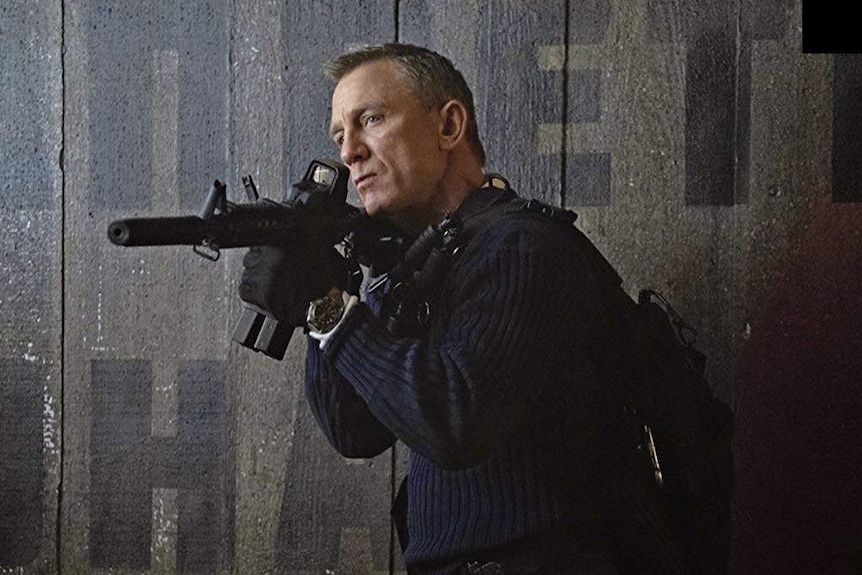 Daniel Craig holds a machine gun