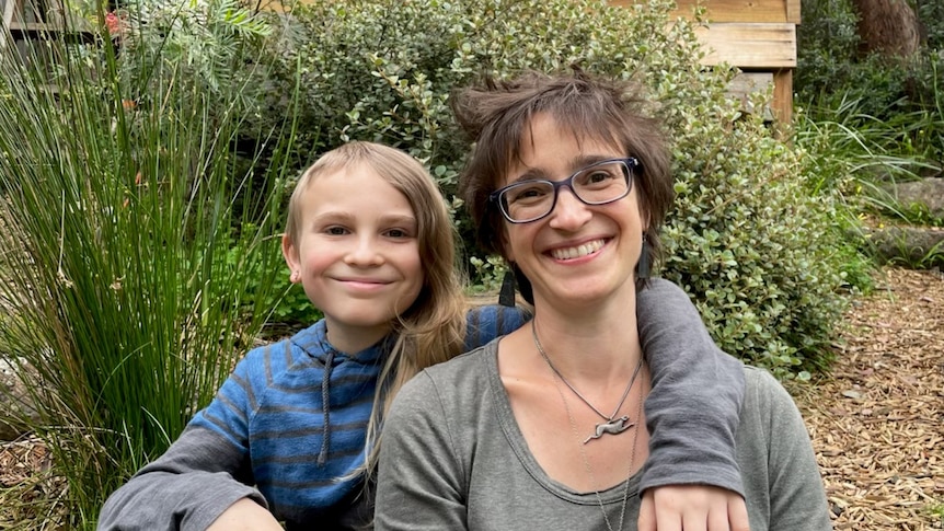 Twelve year old Mani sitting with their mother Zana in a garden.