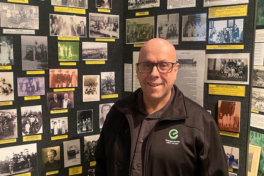 A smiling middle-aged man standing in front of a photo collection