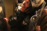 A police officer screams as he is crushed by a metal door.