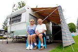 Two retirees, Ray and Annie Barrow, sit in front of their 1960s retro caravan