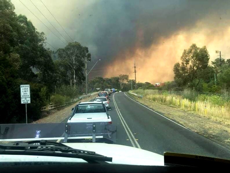 A view from the inside a vehicle looking to a traffic jam in front and bushfire smoke in the distance.