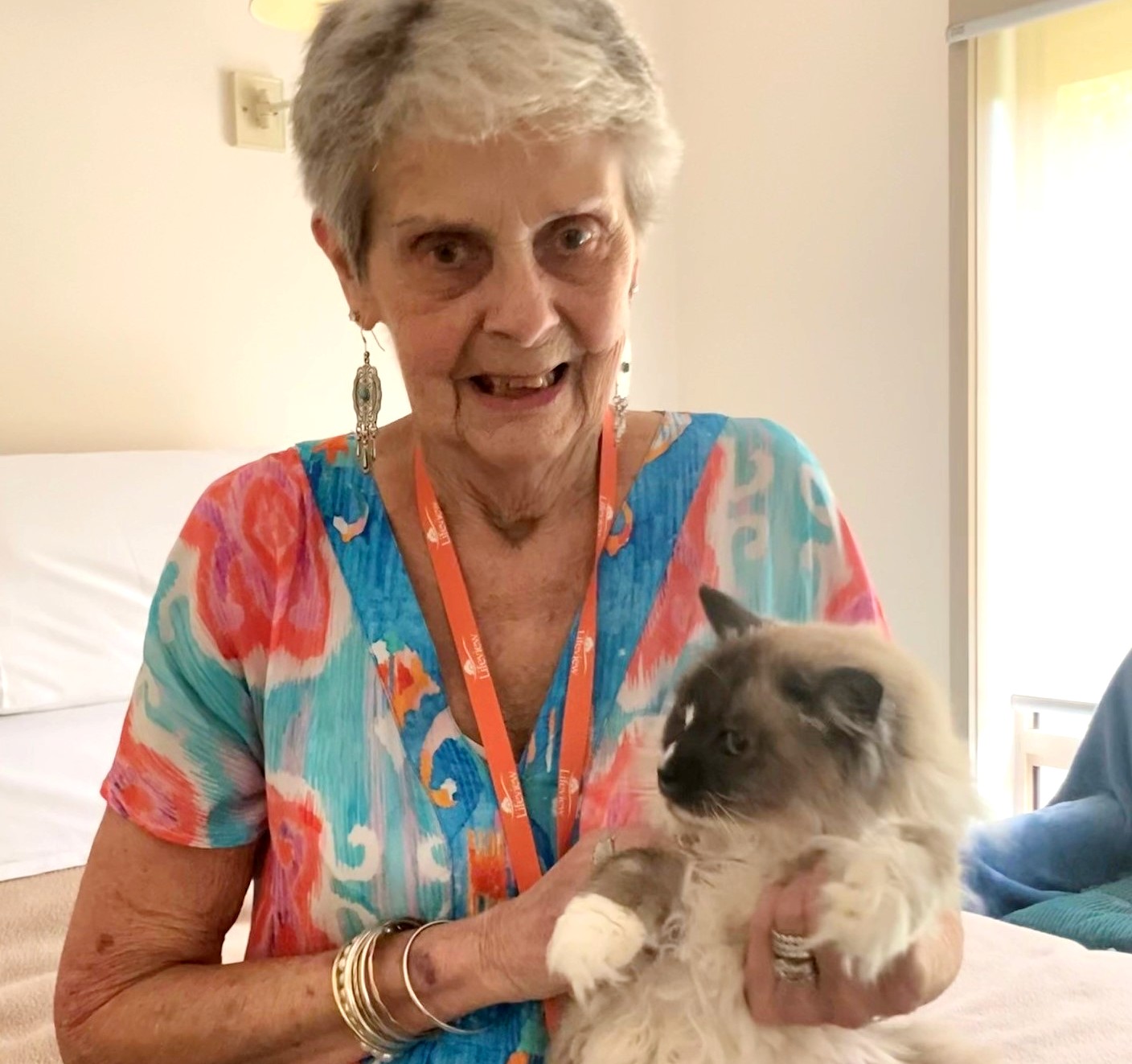 An elderly woman holds a fluffy cat