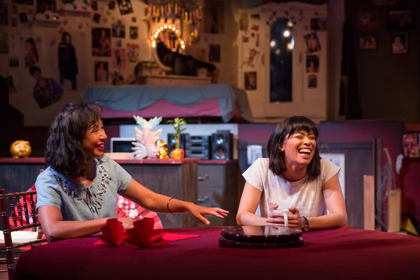 A photo of a play with an Asian-Australian mother and daughter at a table, laughing.