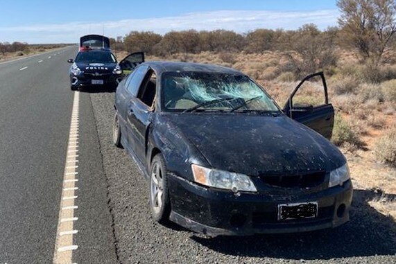 A damaged car pulled over on a rural road.